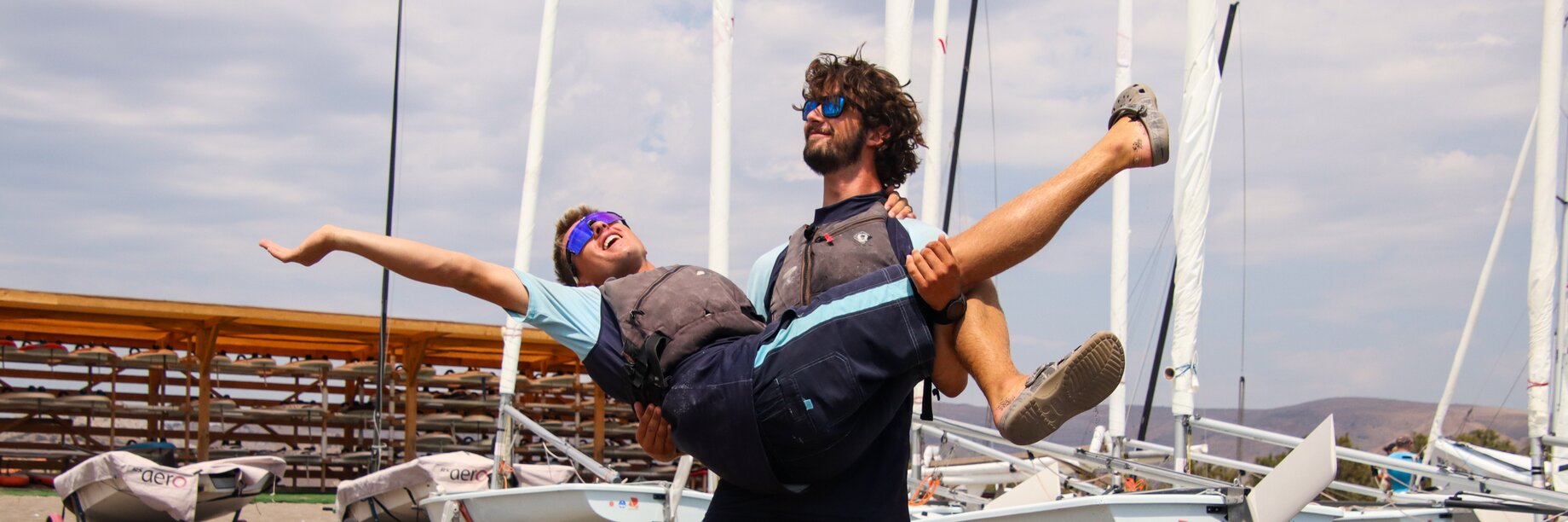 Two staff members pose and smile on the beach at Aeolian Village Beach Resort