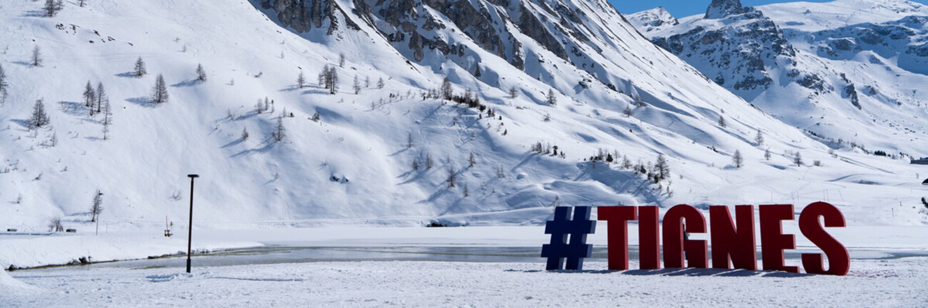 Tignes ski resort sign with a snowy mountainous backdrop