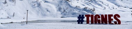 Tignes ski resort sign with a snowy mountainous backdrop