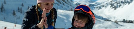 Child high fiving his ski instructor on the piste