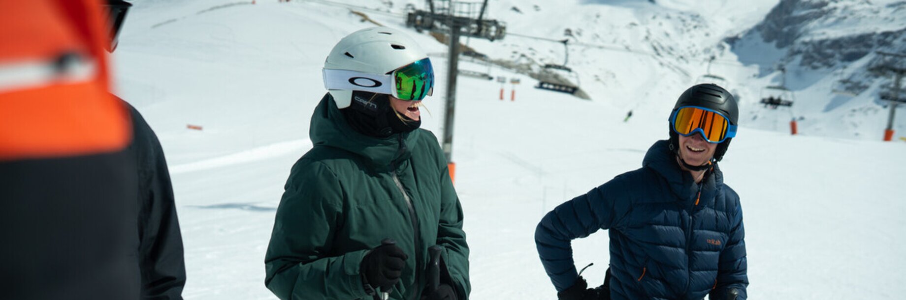 Skiers joking with a view of the chairlift and snowy mountains