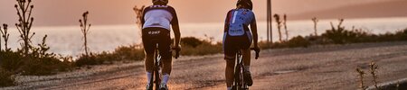 two people riding bikes on a dirt road