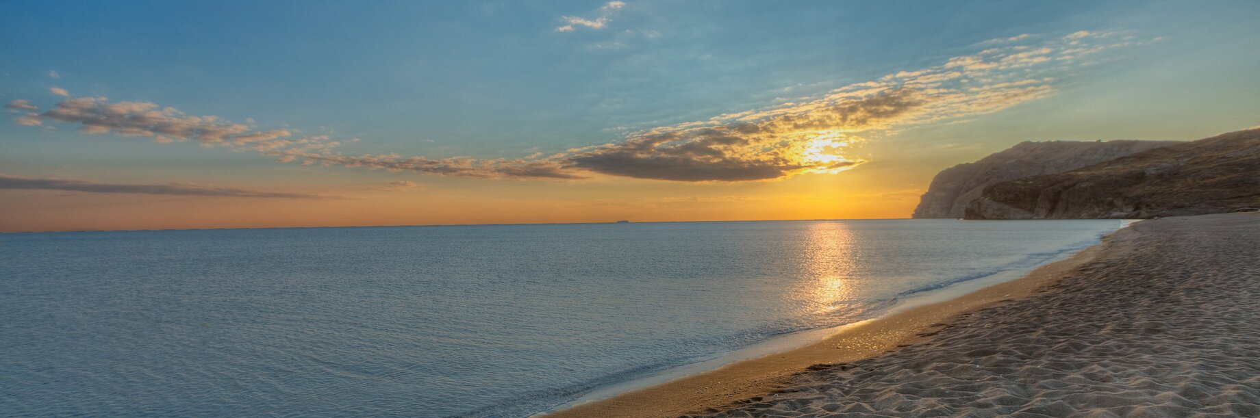 a beach with a body of water and a sunset