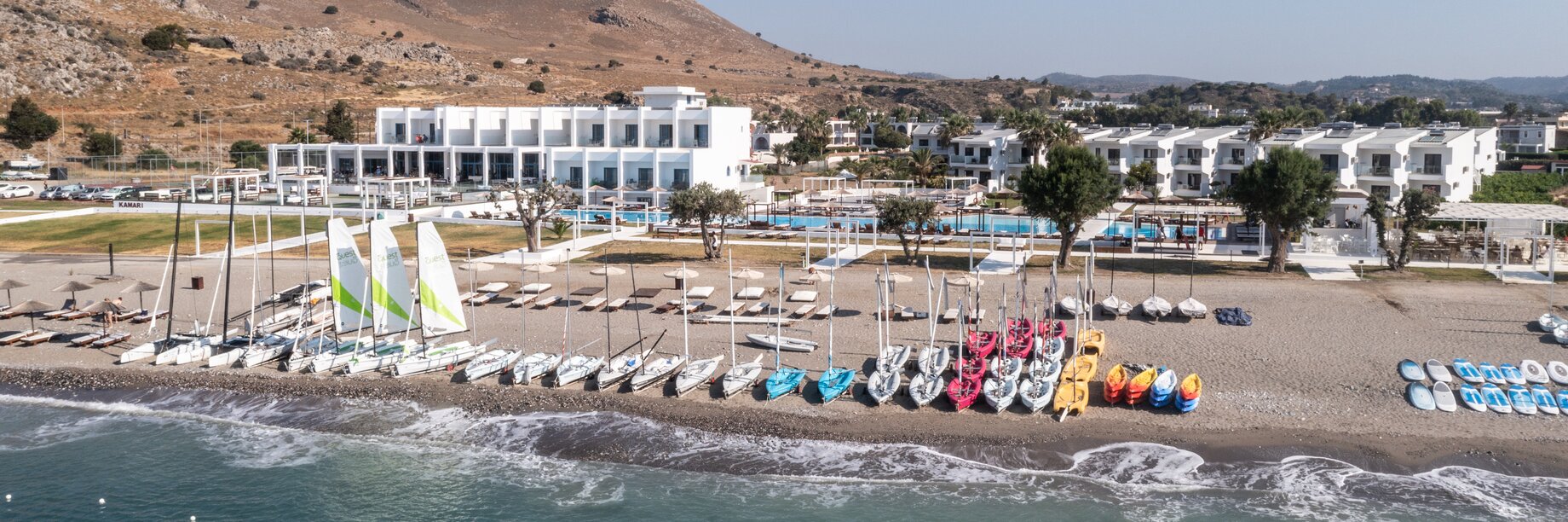 a beach with a building and a hill in the background