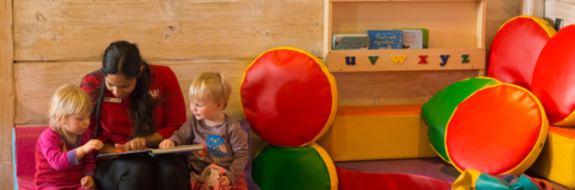Winter childcare staff member reading to two small childcare 