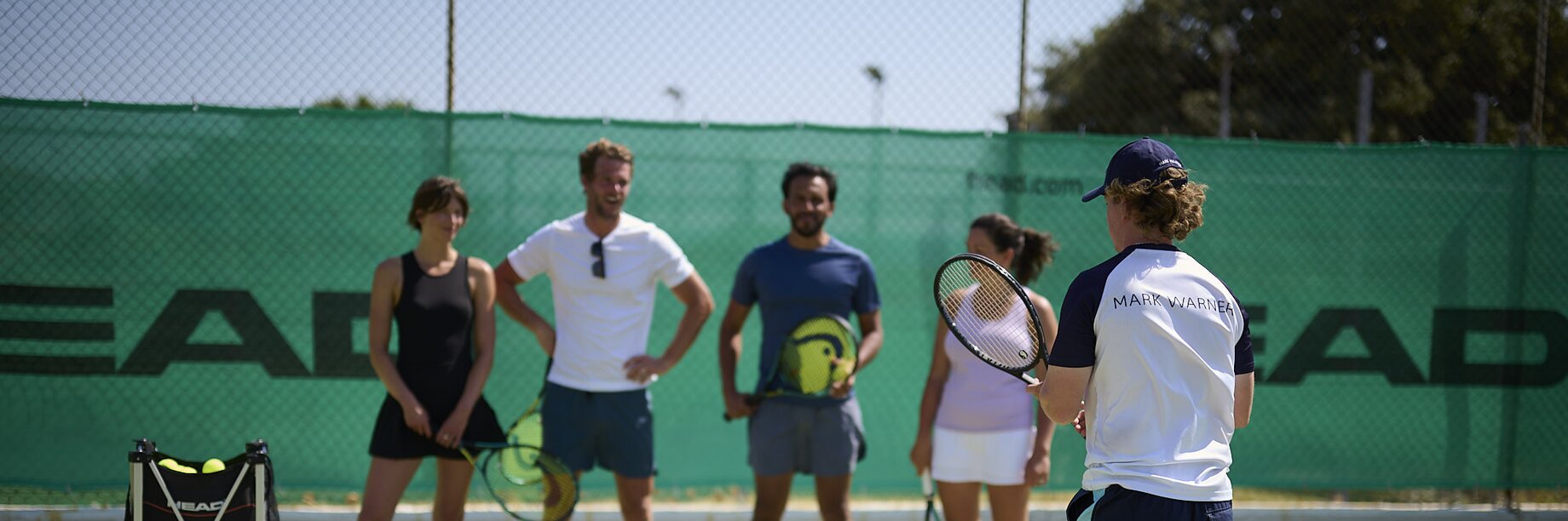A group of people having a tennis coaching lesson with a Mark Warner tennis coach